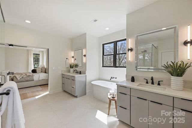 ensuite bathroom with plenty of natural light, a shower stall, visible vents, and a sink