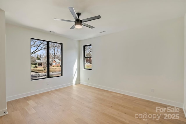 empty room with baseboards, ceiling fan, visible vents, and light wood-style floors