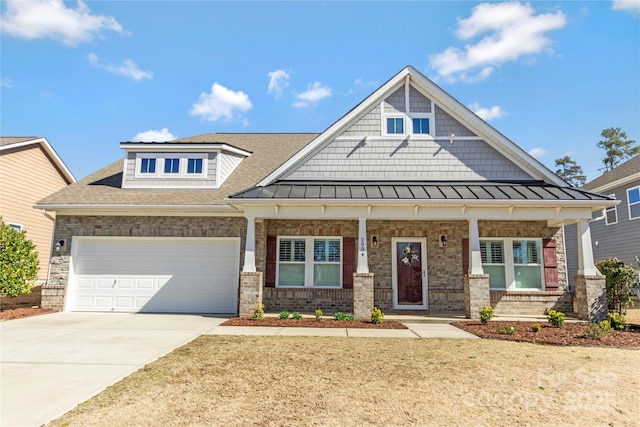 craftsman-style home with an attached garage, covered porch, driveway, and a standing seam roof