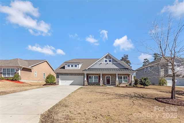 view of front of property featuring driveway, a standing seam roof, stone siding, covered porch, and an attached garage