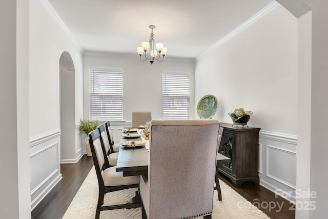 dining space featuring ornamental molding, wainscoting, a notable chandelier, and dark wood-style floors