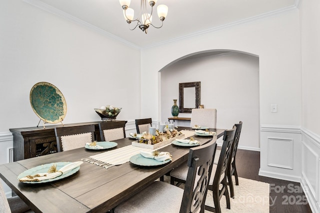 dining area with crown molding, dark wood finished floors, a notable chandelier, and arched walkways