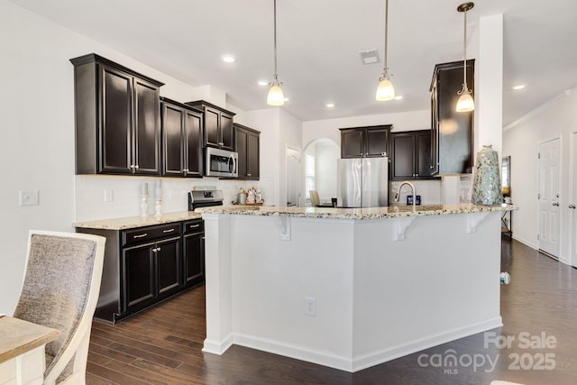 kitchen with arched walkways, stainless steel appliances, dark wood-type flooring, visible vents, and light stone countertops