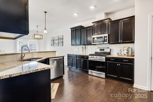 kitchen with dark wood finished floors, light stone counters, a sink, stainless steel appliances, and backsplash