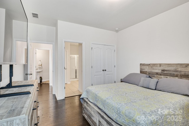 bedroom featuring a closet, visible vents, dark wood-style flooring, and ensuite bathroom