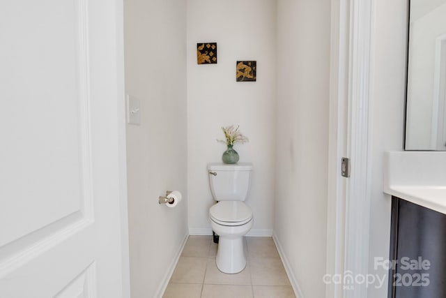 half bath with vanity, tile patterned flooring, toilet, and baseboards