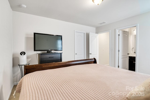 carpeted bedroom featuring baseboards, visible vents, and ensuite bathroom