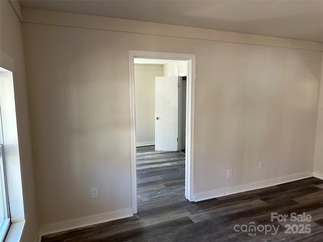 empty room with dark wood-style flooring and baseboards