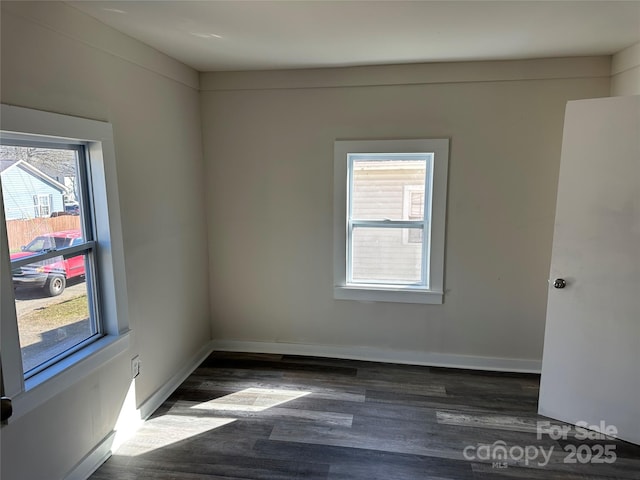 spare room featuring dark wood-type flooring and baseboards