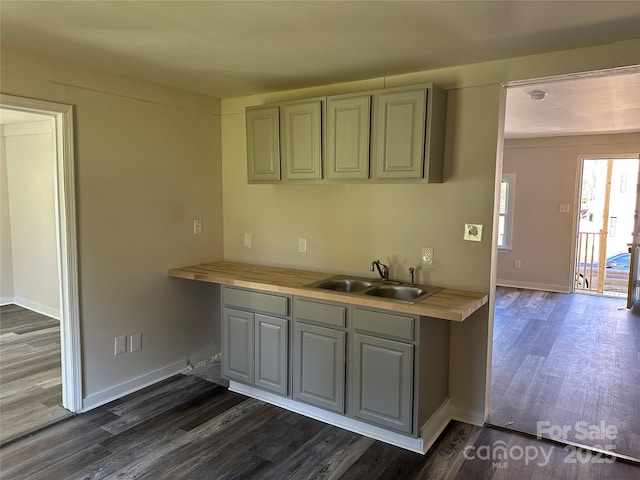 kitchen with dark wood-style floors, light countertops, a sink, and baseboards