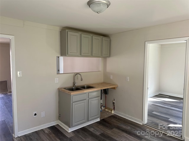 kitchen with dark wood-style floors, gray cabinets, light countertops, a sink, and baseboards