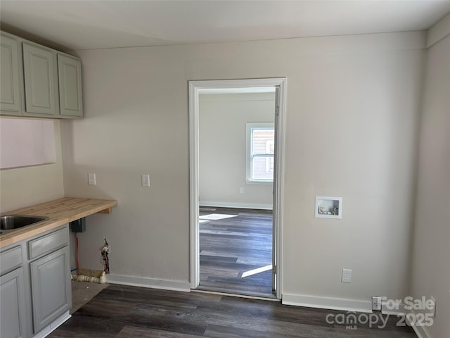 laundry room featuring dark wood-style floors, washer hookup, cabinet space, and baseboards