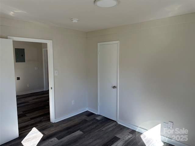 spare room with dark wood-style flooring, electric panel, and baseboards