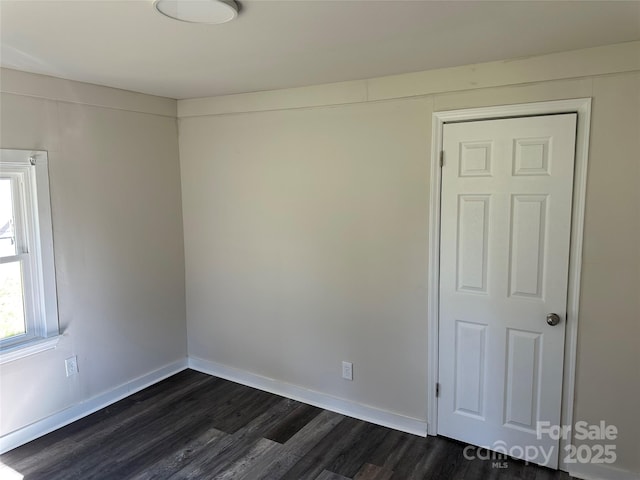 spare room with dark wood finished floors and baseboards