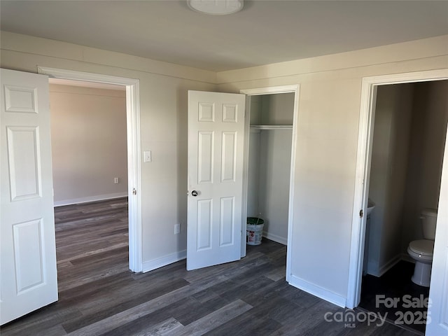 unfurnished bedroom featuring dark wood-type flooring, a closet, and baseboards