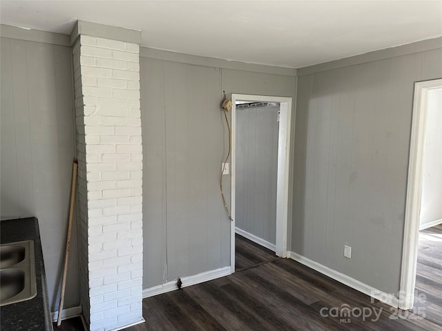 unfurnished room featuring a sink, dark wood finished floors, and baseboards