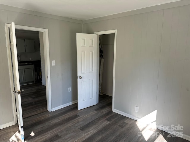 unfurnished bedroom featuring a sink, dark wood finished floors, and baseboards