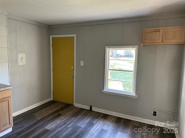 unfurnished dining area featuring dark wood-style flooring and baseboards