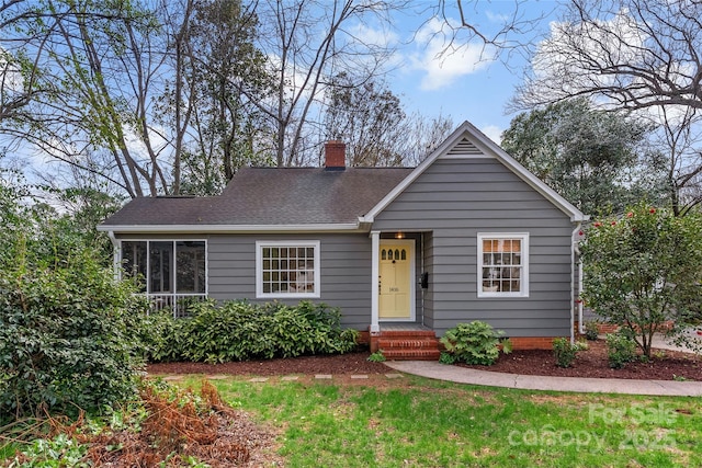 view of front of house with a shingled roof, a chimney, and a front lawn