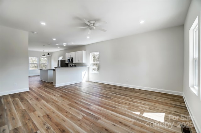 unfurnished living room featuring a ceiling fan, recessed lighting, baseboards, and light wood finished floors