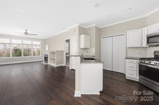 kitchen featuring dark wood-style floors, stainless steel appliances, white cabinetry, a sink, and light stone countertops