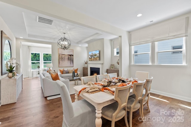305 Basil Dr, Indian Trail, NC 28079 - dining space featuring wood finished floors, a lit fireplace, a raised ceiling, recessed lighting, and a chandelier