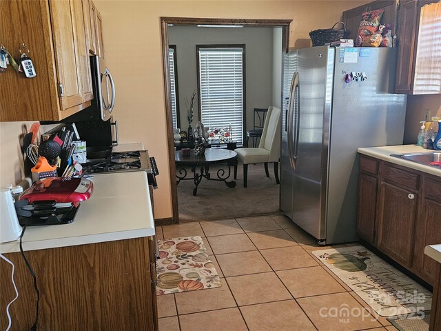 2630 Sloan Dr, Charlotte, NC 28208 - kitchen featuring stainless steel refrigerator with ice dispenser, light countertops, light tile patterned floors, and light colored carpet