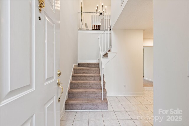 staircase with tile patterned flooring, baseboards, and a chandelier