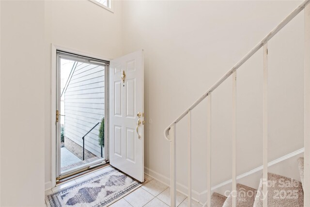 entrance foyer with stairway, baseboards, and light tile patterned floors