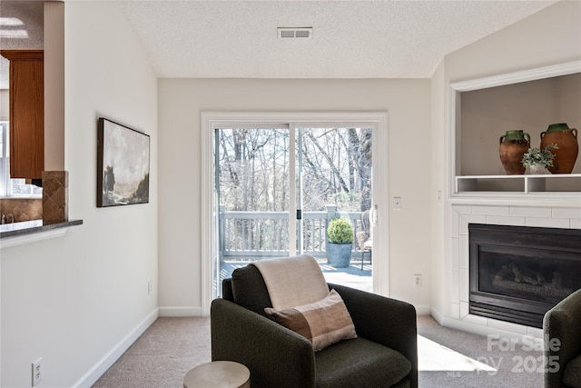 sitting room with carpet, visible vents, a textured ceiling, a tile fireplace, and baseboards