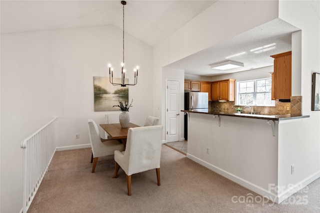 dining area with light carpet, vaulted ceiling, a notable chandelier, and baseboards