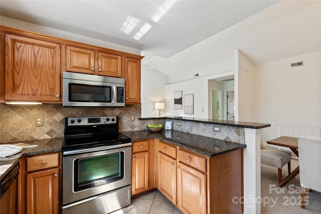 kitchen featuring stainless steel appliances, visible vents, light tile patterned flooring, a peninsula, and a kitchen bar