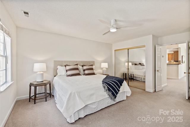 carpeted bedroom featuring baseboards, visible vents, ceiling fan, a textured ceiling, and a closet