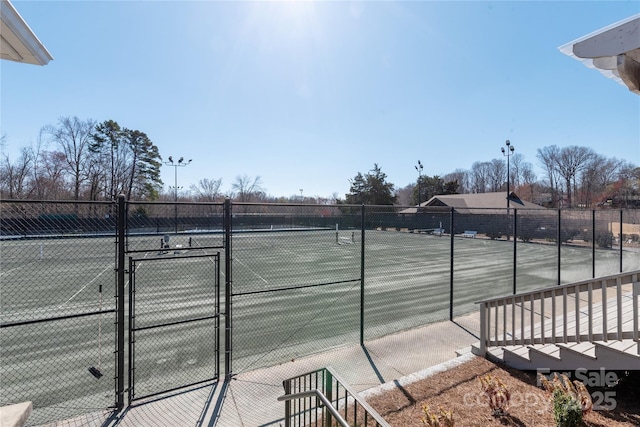 view of tennis court featuring fence and a gate