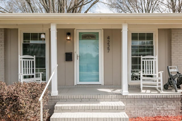 property entrance with a porch and brick siding