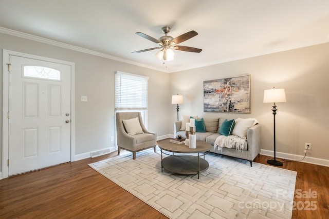 living room with ornamental molding, visible vents, baseboards, and wood finished floors