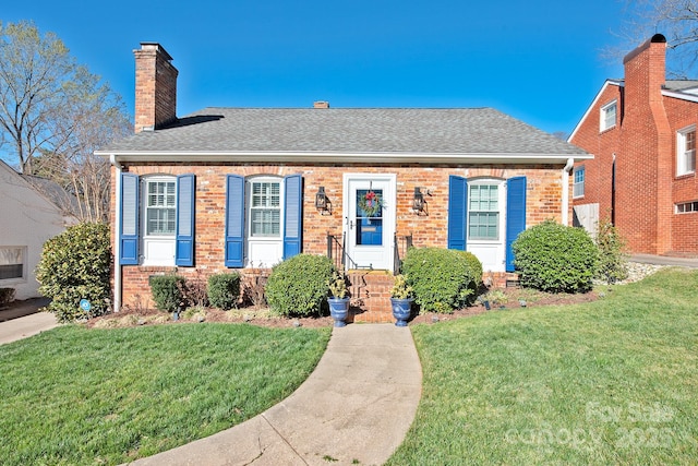 bungalow-style house with a shingled roof, brick siding, a chimney, and a front lawn