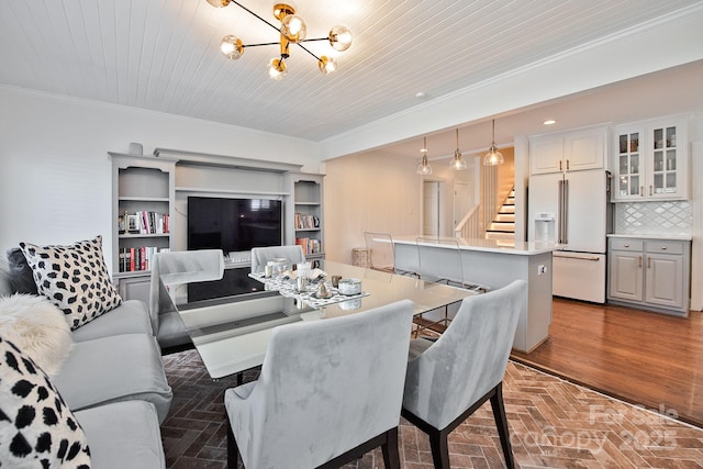 living area featuring ornamental molding, stairway, brick floor, and an inviting chandelier