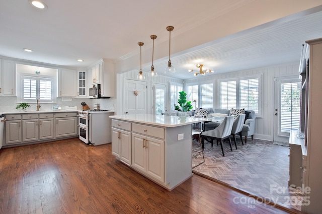 kitchen featuring range with two ovens, dark wood finished floors, stainless steel microwave, a breakfast bar, and a center island