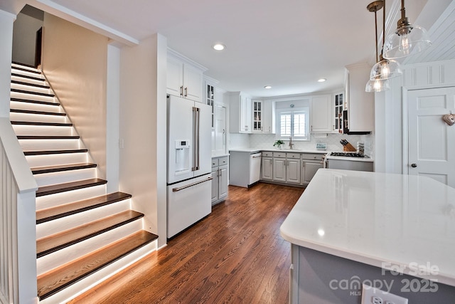 kitchen with gray cabinetry, high end fridge, range, dark wood finished floors, and glass insert cabinets