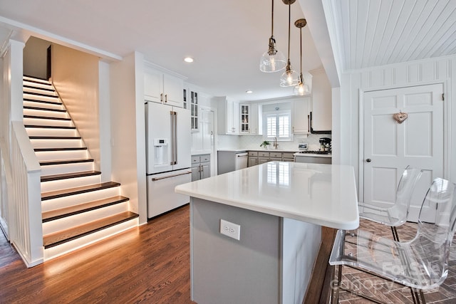 kitchen featuring a sink, high end fridge, light countertops, dark wood finished floors, and glass insert cabinets