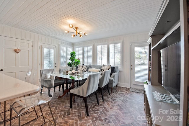 dining space featuring wooden ceiling, brick floor, ornamental molding, and a notable chandelier