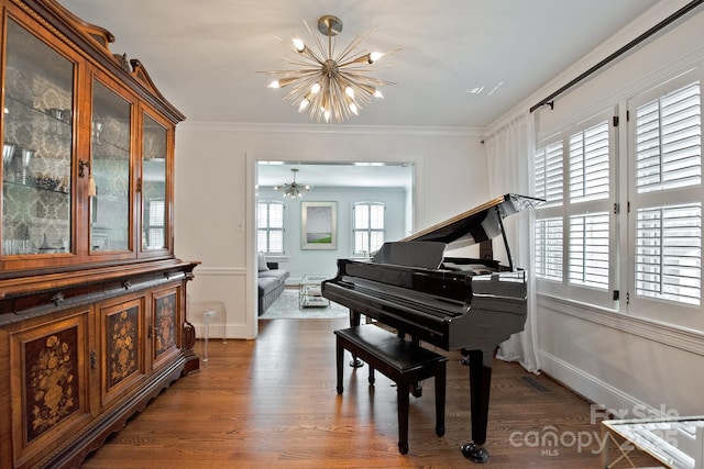 living area featuring crown molding, baseboards, wood finished floors, and a notable chandelier