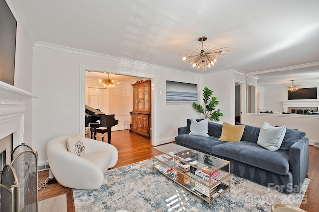 living area with ornamental molding, a notable chandelier, a fireplace, and wood finished floors