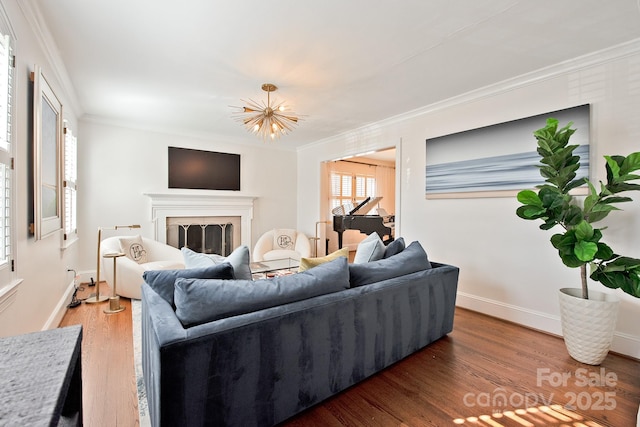 living area with ornamental molding, a fireplace, baseboards, and wood finished floors