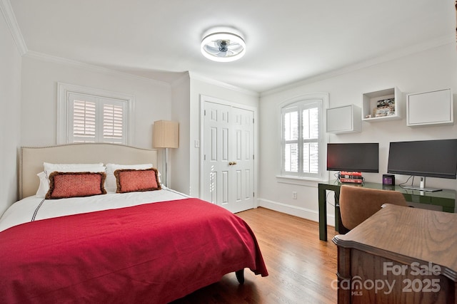 bedroom featuring baseboards, a closet, wood finished floors, and crown molding