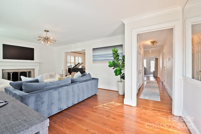 living room featuring light wood-type flooring, a fireplace, crown molding, and baseboards