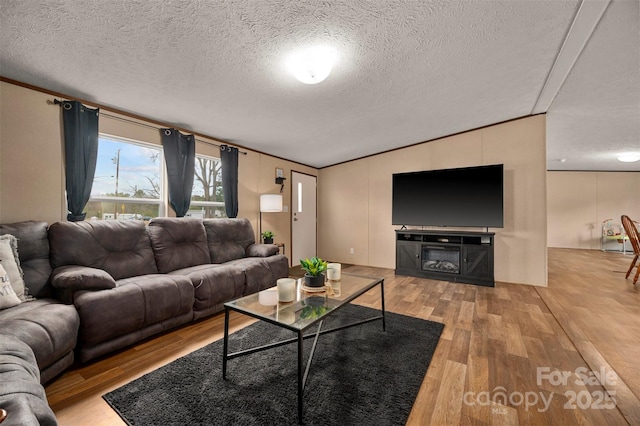 living room featuring ornamental molding, lofted ceiling, a textured ceiling, and wood finished floors