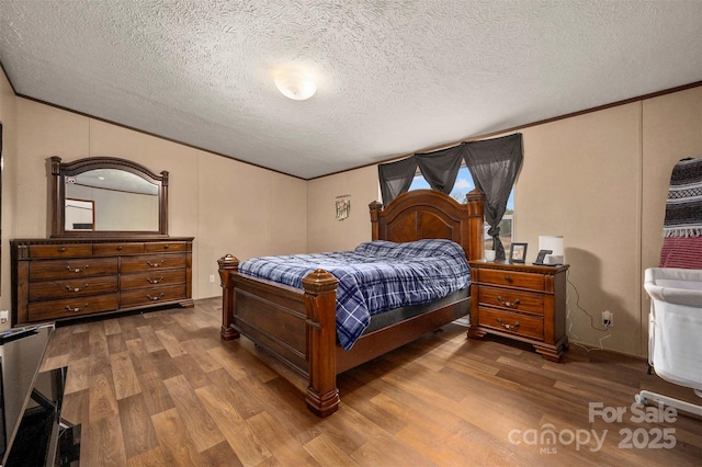 bedroom featuring crown molding, a textured ceiling, and wood finished floors