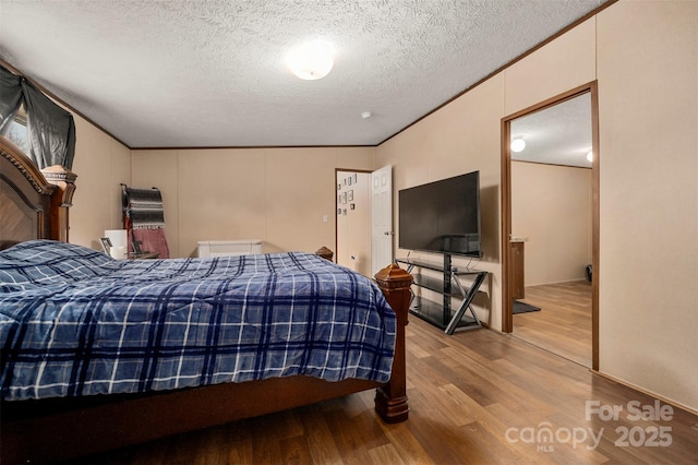 bedroom featuring crown molding, a textured ceiling, and wood finished floors